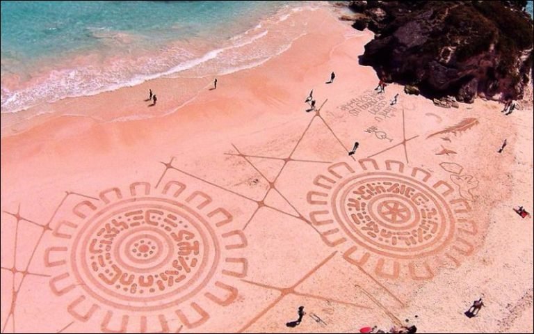 Aerial view of a pink sand beach with people walking and enjoying the scenery.